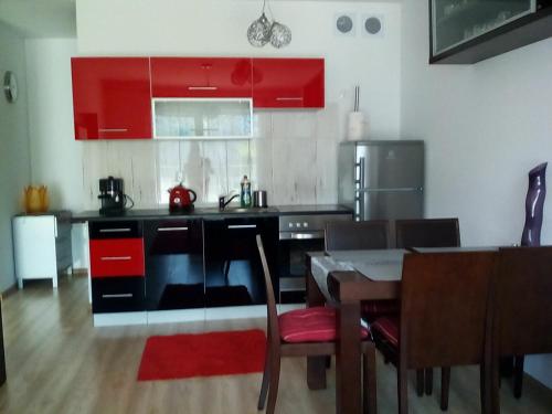 コウォブジェクにあるKarmazynowy Apartament Nad Morzemのキッチン(赤いキャビネット、テーブル、椅子付)