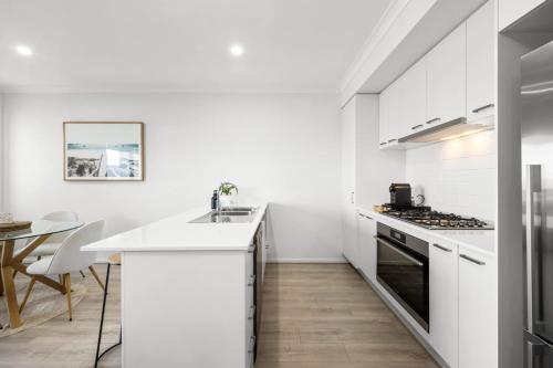 a white kitchen with a counter and a table at Cherry St Retreat Armstrong Creek in Marshalltown