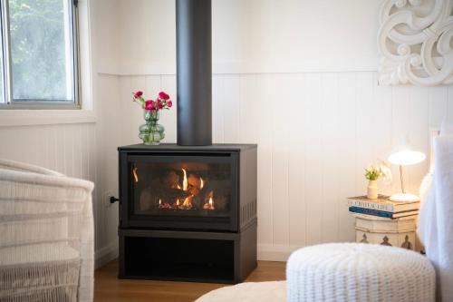a fireplace in a living room with a vase of flowers at Lady Rose Cottage Jamberoo in Jamberoo