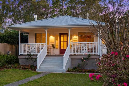 a small white house with a porch and stairs at Lady Rose Cottage Jamberoo in Jamberoo