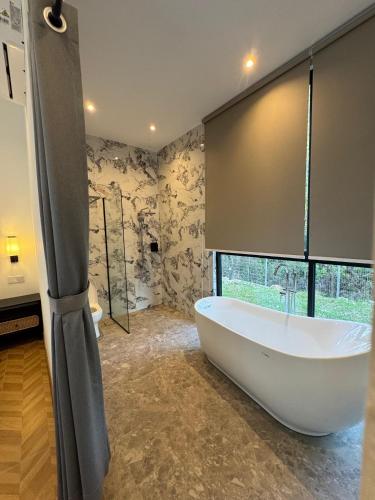 a large bath tub in a bathroom with a window at The Rubber Escape, Melaka in Melaka