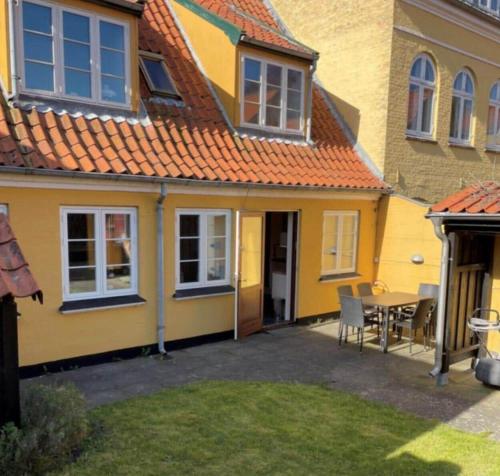 a yellow house with a table in a yard at AE258-Aeroskobing-Sondergade-3 in Ærøskøbing