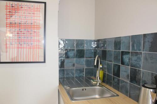a kitchen with a sink and a picture on the wall at La Bullote - Gîtes - Paris Roissy CDG in Villeneuve-sous-Dammartin