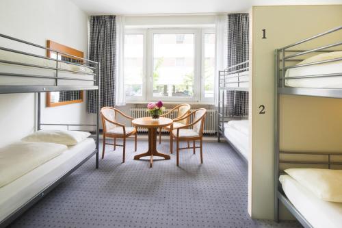 a room with a table and chairs and bunk beds at Airport Hostel in Hamburg