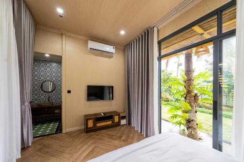 a bedroom with a bed and a tv and a window at Lumiere Family Village Long Khánh - Đồi Rìu in Long Khanh