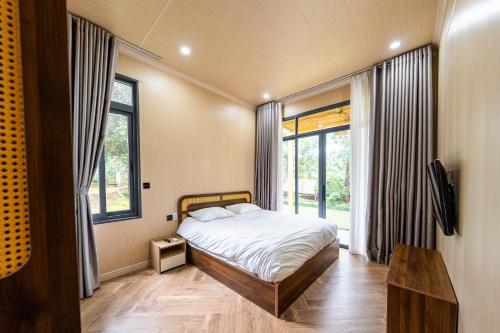 a bedroom with a bed and a large window at Lumiere Family Village Long Khánh - Đồi Rìu in Long Khanh