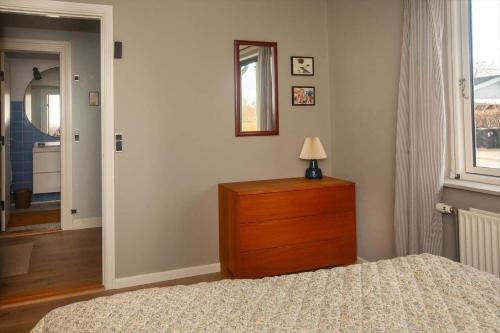 a bedroom with a bed and a dresser with a lamp on it at AE265-Aeroskobing-Sotoften-12 in Ærøskøbing