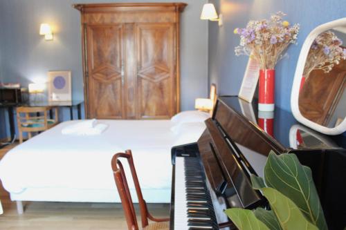 a bedroom with a piano and a bed with a dresser at La Bullote - Gîtes - Paris Roissy CDG in Villeneuve-sous-Dammartin