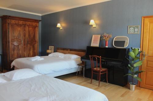 a hotel room with two beds and a piano at La Bullote - Gîtes - Paris Roissy CDG in Villeneuve-sous-Dammartin