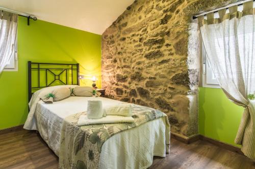 Un dormitorio con una cama con una pared de piedra. en Casa Carla, en Palas de Rei 