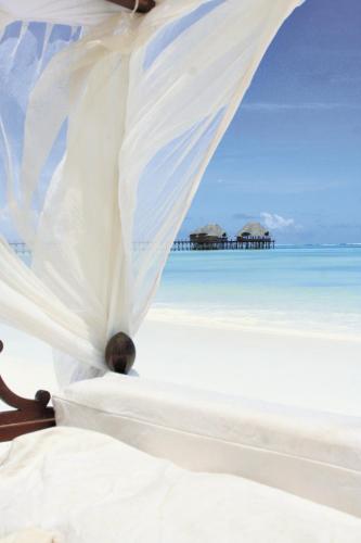 a bed on a beach with the ocean in the background at Hotel Club Dongwe in Pingwe