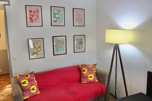 a living room with a red couch and pictures on the wall at La Bullote - Gîtes - Paris Roissy CDG in Villeneuve-sous-Dammartin