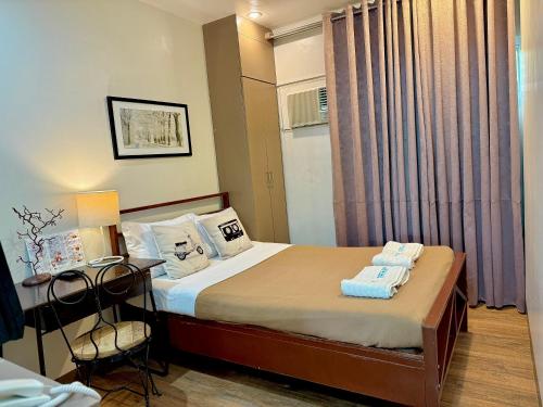 a bedroom with a bed and a table and a chair at Hotel Tiffany - Laoag in Laoag