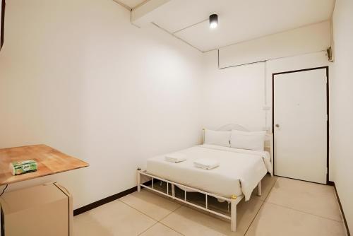 a white bedroom with a bed and a desk at XX GO INN Asiatique Bangkok โก อินน์ เอเชียทีค เจริญกรุง in Bangkok
