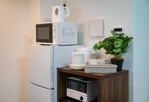 a microwave sitting on top of a wooden stand next to a refrigerator at Hotel the World Omori in Tokyo
