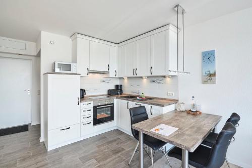 a kitchen with white cabinets and a table with chairs at Frische Brise - 1504 in Cuxhaven