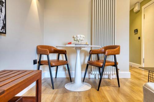 a table with two chairs and a table with a cake on it at City Oasis Craigpark Residence in Glasgow