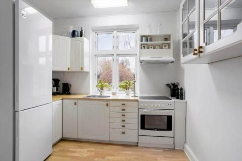 a white kitchen with white cabinets and a window at AE303-Aeroskobing-Sygehusvejen-3 in Ærøskøbing