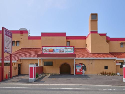 a building with a red roof and a gas station at Tabist Centro Chita in Minamichita