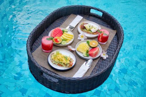 a round table with plates of food and drinks next to a swimming pool at Maithala Villa Kuta Bali Near Airport in Kuta