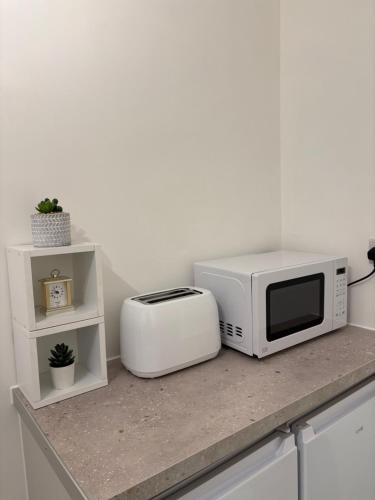 a microwave and a toaster sitting on a counter at Newly Refurbished - Stylish - Modern - And Cosy Flat - King Size Bed with Built In Speakers - Bedside Lamp - And USB Ports - Sofa Bed - In Islington North London in London