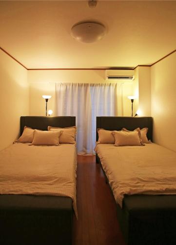 two beds sitting next to each other in a room at SN62 大須駅鶴舞駅最寄り 栄まで徒歩圏内 最大12名 3家族分の個室 お風呂からのスカイビュー Nearst to Osu Tsuruma Station Within walking distance to Sakae Private room for up to 12 people 3 families Sky view from the bath in Nagoya