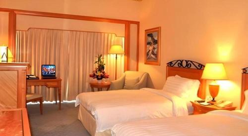 a hotel room with two beds and a desk at Regency Hotel in Shantou