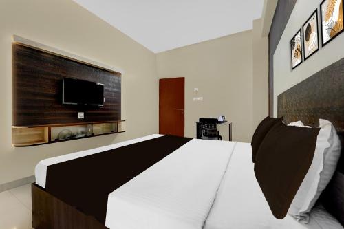 a bedroom with a large bed and a flat screen tv at Collection O Republic Mall Coimbatore Formerly Manis Residency in Coimbatore