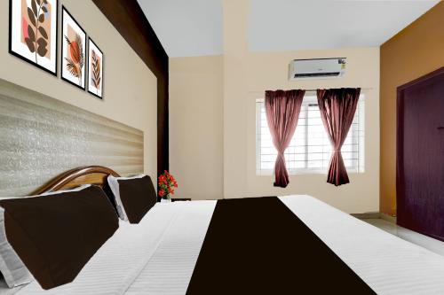 a bedroom with a black and white bed and a window at Collection O Republic Mall Coimbatore Formerly Manis Residency in Coimbatore