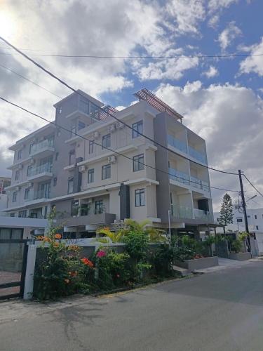 a large white building with flowers in front of it at Apartment in Flic en Flac - Pearl Side Residence 101 in Flic-en-Flac