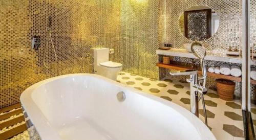 a bathroom with a tub and a shower and a toilet at Le Pavillon Hoi An Paradise Hotel & Spa in Hoi An