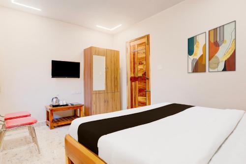 a white bedroom with a bed and a television at Super Townhouse Sri Padmavati Ammavaari Temple Formerly Hotel Rama Grand in Tirupati