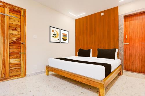 a bedroom with a bed and a wooden door at Super Townhouse Sri Padmavati Ammavaari Temple Formerly Hotel Rama Grand in Tirupati