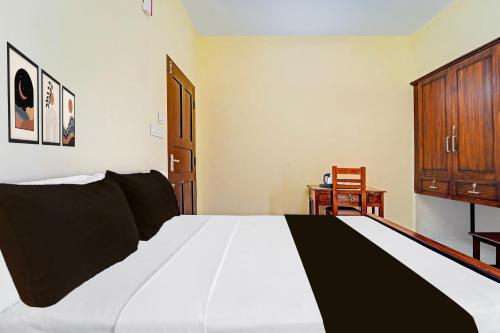 a bedroom with a bed and a wooden cabinet at Super Hotel O Omalloor Temple Formerly MTS Lodge in Pathanāmthitta