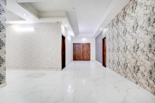a corridor with white tile floors and a wooden door at Collection O Palwal-Aligarh Crossway Formerly Hotel Kadamb in Palwal
