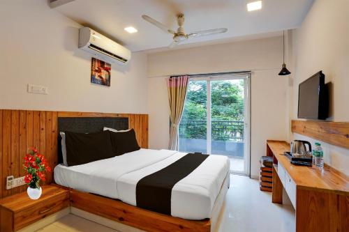 a bedroom with a bed and a desk and a television at Super Townhouse Oak Gravity Inn in Pune