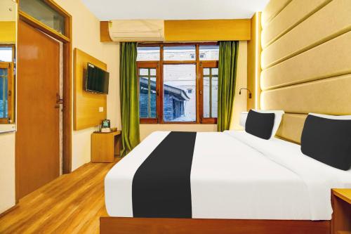 a bedroom with a white and black bed and a window at Super Townhouse Rajbagh Formerly Hotel Modern in Srinagar