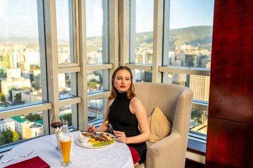 a woman sitting at a table with a plate of food at Best Western Premier Tuushin Hotel in Ulaanbaatar