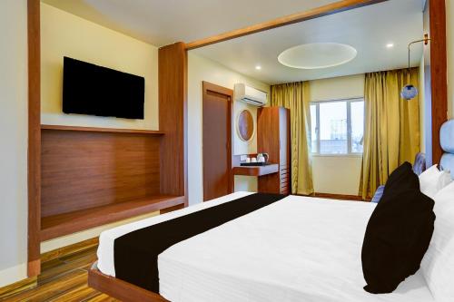 a bedroom with a large white bed and a flat screen tv at Super Townhouse Zero Mile Gandhi Setu Formerly Classic Court in Gulzārbāgh