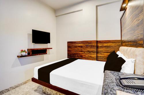 a bedroom with a large bed and a tv at Super Townhouse Zero Mile Gandhi Setu Formerly Classic Court in Gulzārbāgh