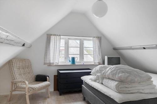 a bedroom with a bed and a chair and a window at 20331-Samso-Vestergade-37 in Kolby