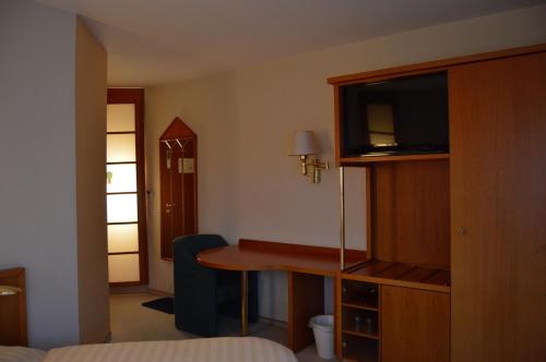 a hotel room with a desk with a television and a bed at Hotel Stadt Jessen in Jessen