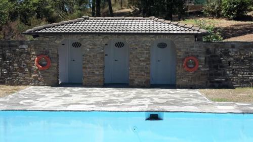 a stone building with four doors next to a swimming pool at Villa Azzurra in Arezzo