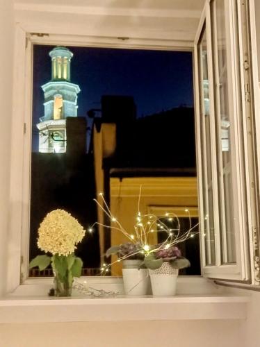 a window with flowers on a window sill with a lighthouse at 1 room in Poznań