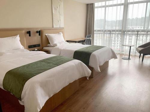 a hotel room with two beds and a large window at GreenTree Inn Yichun Mingyueshan Airport in Yichun