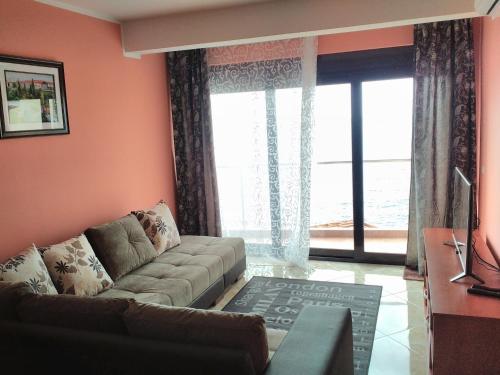 a living room with a couch and a large window at Apartment Sea Space in Dobra Voda