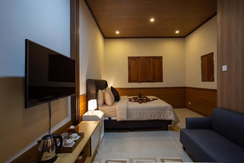 a hotel room with a bed and a flat screen tv at Griya D'Carik in Perean