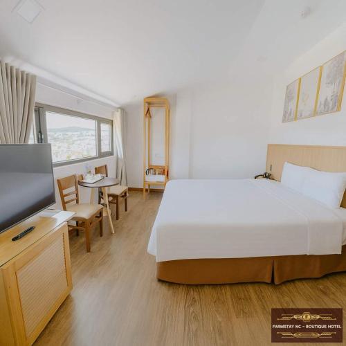 a hotel room with a bed and a television at Farmstay NC - Boutique Hotel in Da Lat