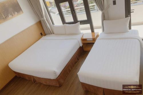 two beds in a small room with a window at Farmstay NC - Boutique Hotel in Da Lat