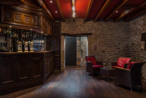 a bar with red chairs and a stone wall at Manoir de Kerhuel de Quimper in Plonéour-Lanvern